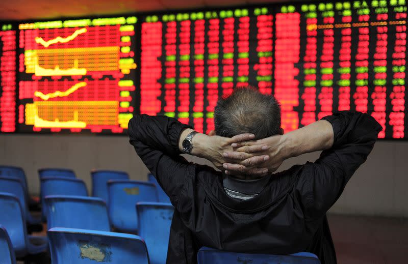FILE PHOTO: An investor places his hands on the back of his head in front of an electronic board showing stock information at a brokerage house in Hefei
