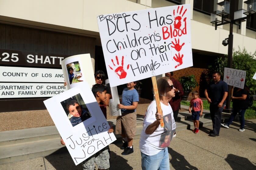 LOS ANGELES, CALIF. -- THURSDAY, AUGUST 1, 2019: Donna Estevez, of Baldwin Park, right, whose grandchild Aramazd Andressian, five, was killed by his father in April 2017, along with a child, left, holding a sign with the photo of Noah Cuatro, four, who died July 6, 2019 in his parents' custody, before Attorney Brian Claypool holds a press conference announcing a $50 million lawsuit against the Los Angeles County Department of Children Services in the death of Anthony Avalos, the 10-year-old Antelope Valley boy prosecutors say was killed by his parents after sustained abuse, in front of DCF offices in Los Angeles, Calif., on Aug. 1, 2019. (Gary Coronado / Los Angeles Times)