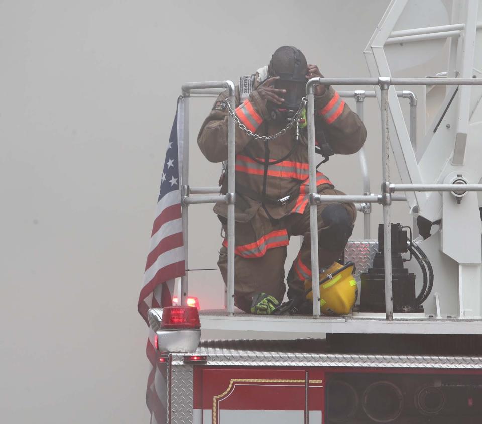 An Akron firefighter puts on his oxygen mask as he becomes engulfed in smoke while manning the water tower truck as firefighters work to control a fire Friday at Pavona's Pizza Joint on Sand Run Road.