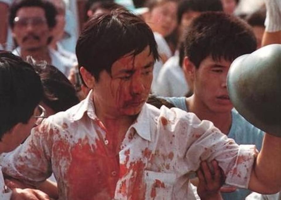 1989年6月3日，人民大會堂前民眾與軍警發生衝突，一位工人被毆打得滿身是血，手中仍抓住一頂軍人在衝突中失落的鋼盔。(圖:六四檔案)