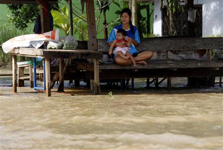A woman and her baby sit on a bench on a flooded street at Srimahaphot district in Prachin Buri province, east of Bangkok September 24, 2013. REUTERS/Chaiwat Subprasom