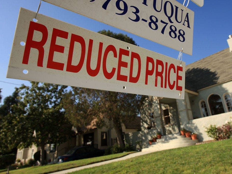 A realtor sign advertises that the price of a house has been reduced