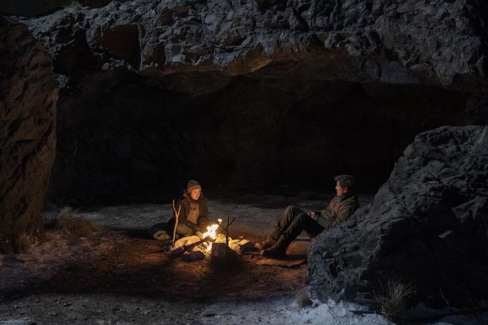 Bella Ramsey's Ellie and OPedro Psacal's Joel sit by a fire in a cave at night on The Last of Us