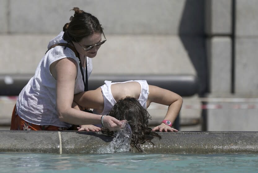 A person wets their hair in a fountain at Trafalgar Square in central London, Tuesday July 19, 2022. Millions of people in Britain woke from the country's warmest-ever night on Tuesday and braced for a day when temperatures could break records, as a heat wave scorching Europe walloped a country not built for such extremes (Aaron Chown/PA via AP)