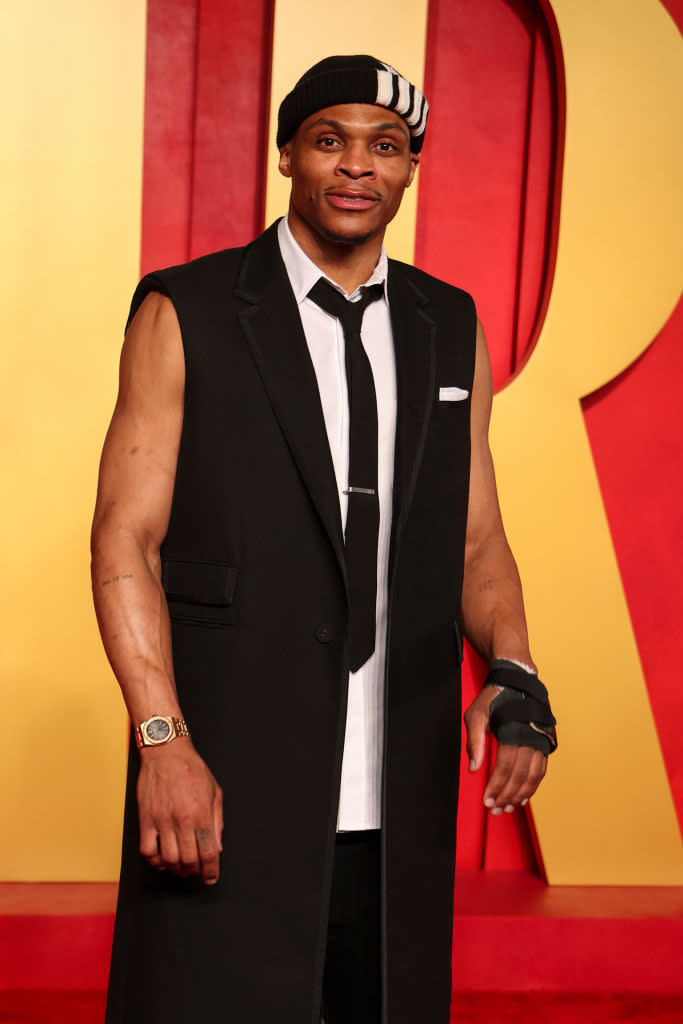 Man in sleeveless tuxedo with wristbands, standing at a formal event