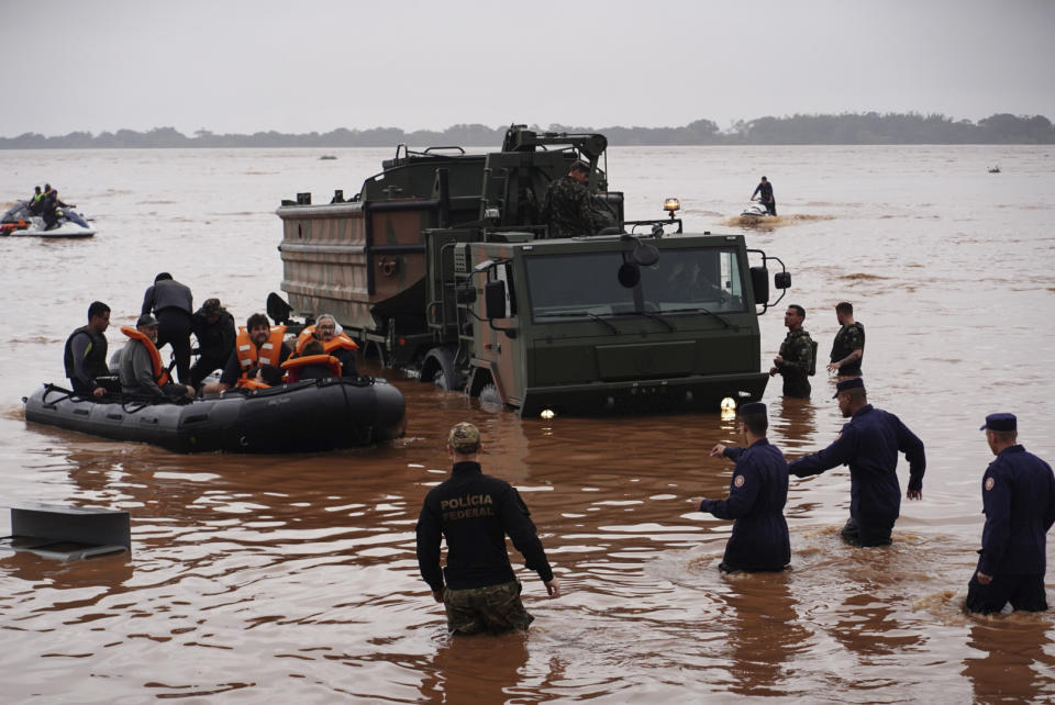 Brazilian soldiers and federal police evacuate residents from an area flooded by heavy rains in Porto Alegre, Rio Grande do Sul state, Brazil, Saturday, May 4, 2024. (AP Photo/Carlos Macedo)