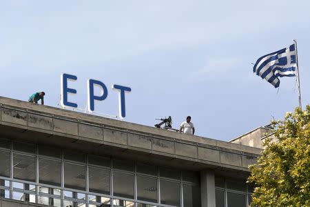 A Greek national flag flutters next to the newly installed logo of the Hellenic Broadcasting Corporation (ERT) in Athens June 8, 2015. REUTERS/Alkis Konstantinidis