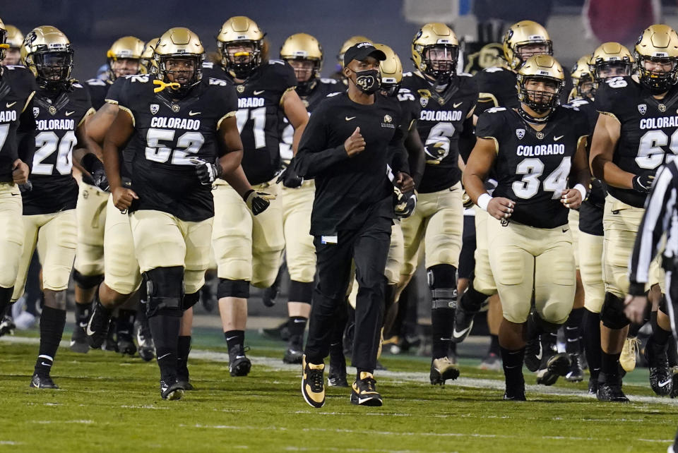 FILE - In this Nov. 7, 2020, file photo, Colorado head coach Karl Dorrell, center, leads his players onto the gridiron to host UCLA in an NCAA college football game in Boulder, Colo. Dorrell was selected as the PAC-12 coach of the year. (AP Photo/David Zalubowski, File)