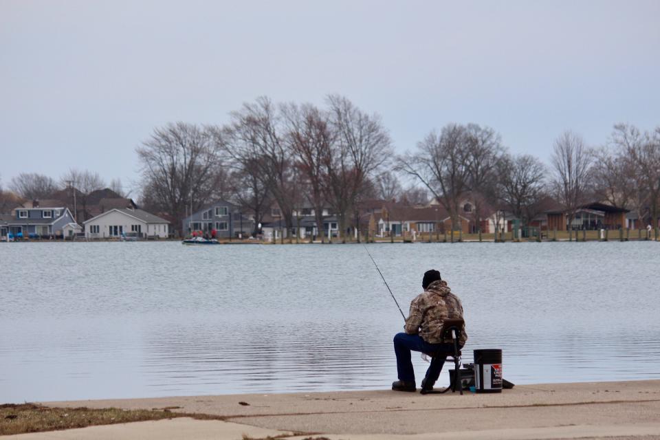 A man sits in his chair in hopes of catching a fish at Black Creek on Thursday, March 26, 2020, at Lake St. Clair Metropark in Harrison Township.