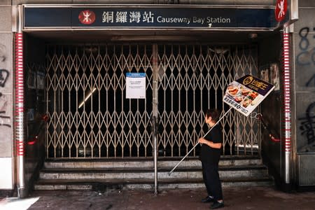 A woman looks at a vandalised metro station entrance that remains closed in Causeway Bay district, in Hong Kong