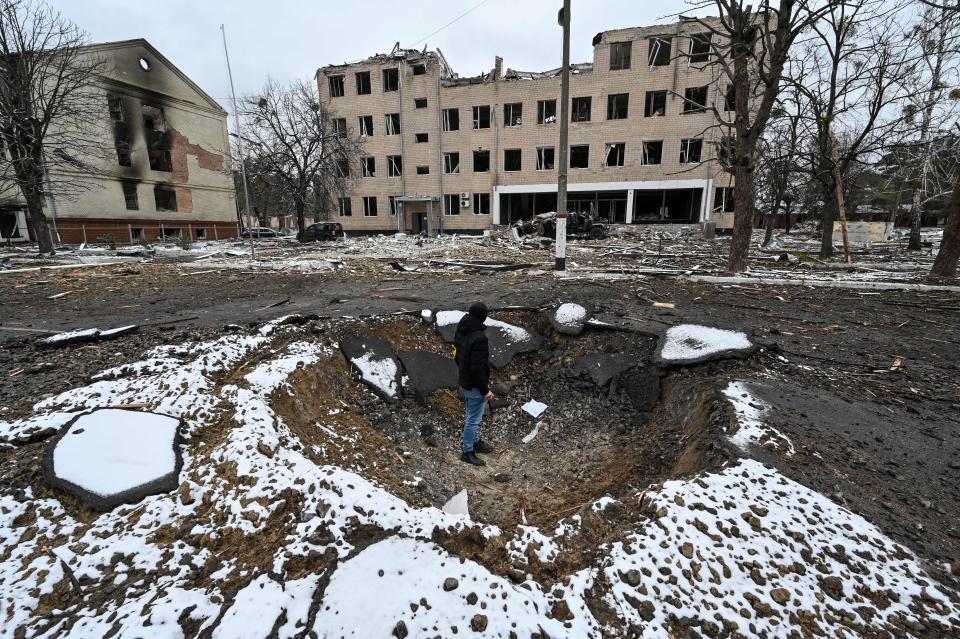 A person stands looking at a partially destroyed military building in Brovary, Ukraine.