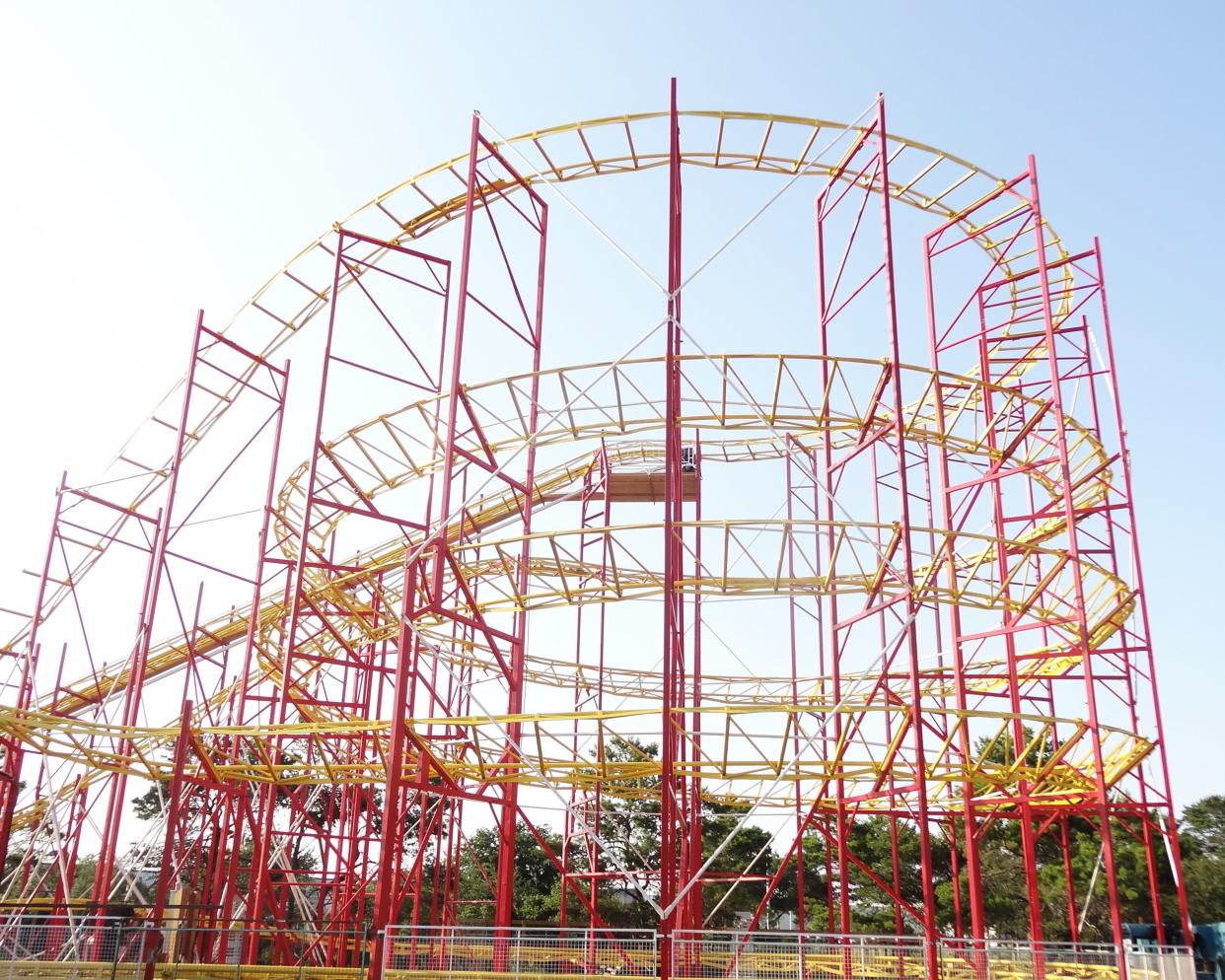 Abandoned Miracle Strip Amusement Park, Panama City Beach, Florida, red and yellow RipTide ride, trees in the background, with a bright blue sky