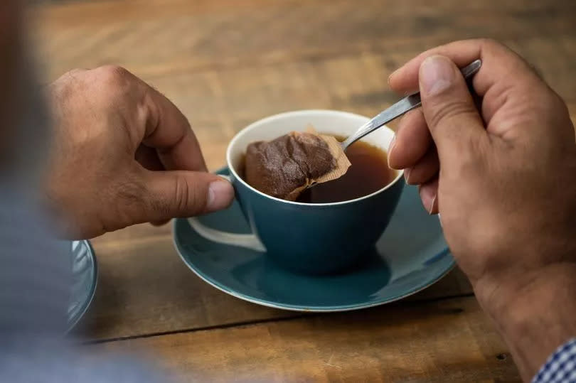 Unrecognisable making a cup of tea by squeezing the tea bag in the cup