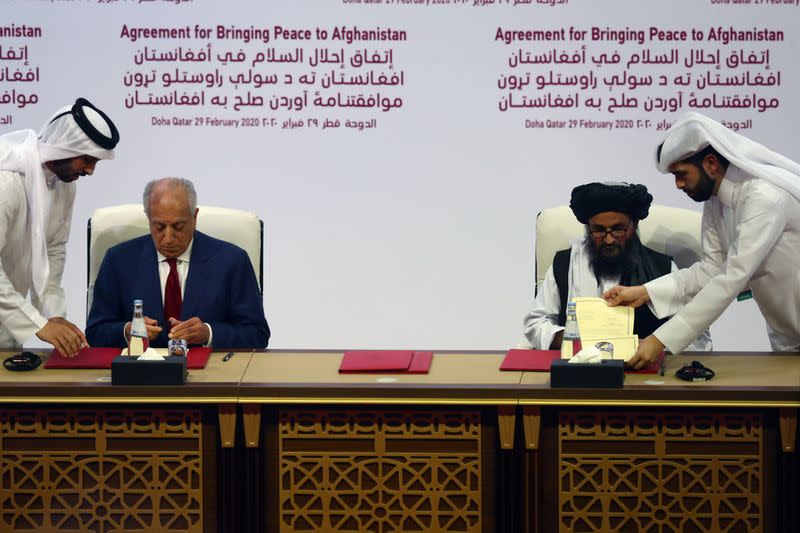 Mullah Abdul Ghani Baradar, the leader of the Taliban delegation, signs an agreement with Zalmay Khalilzad, U.S. envoy for peace in Afghanistan, at a signing agreement ceremony between members of Afghanistan's Taliban and the U.S. in Doha