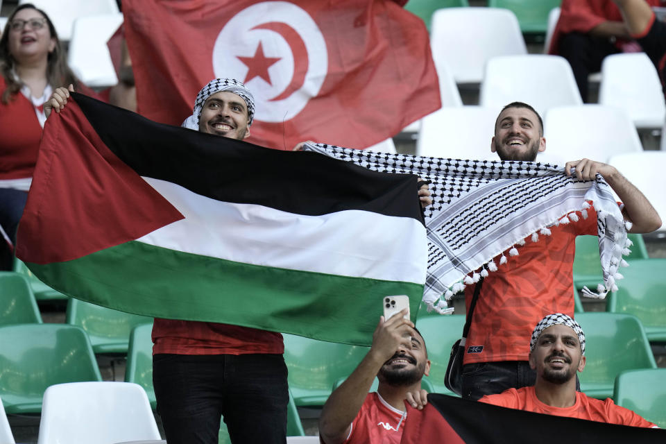 A soccer supporter waves a flag of Palastine before the start of the World Cup group D soccer match between Denmark and Tunisia, at the Education City Stadium in Al Rayyan , Qatar, Tuesday, Nov. 22, 2022. (AP Photo/Hassan Ammar)