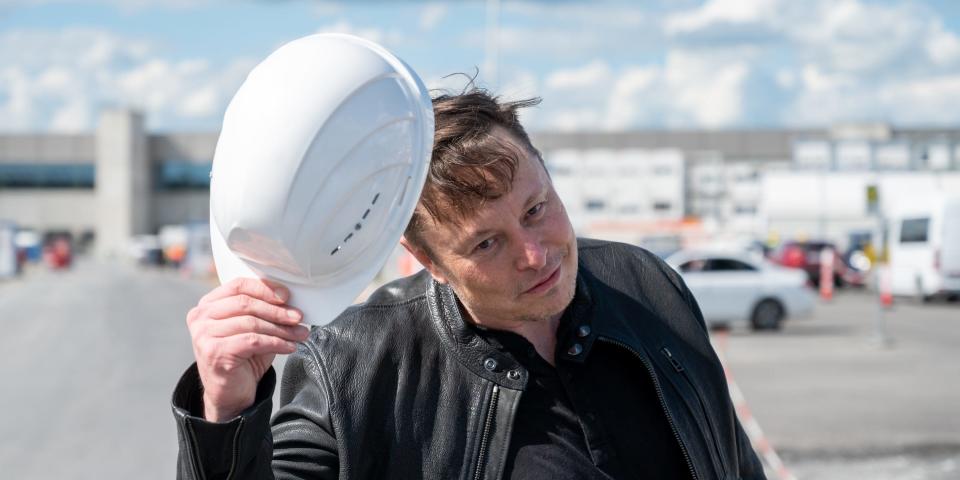 Elon Mush holds a Tesla-branded hard hat.