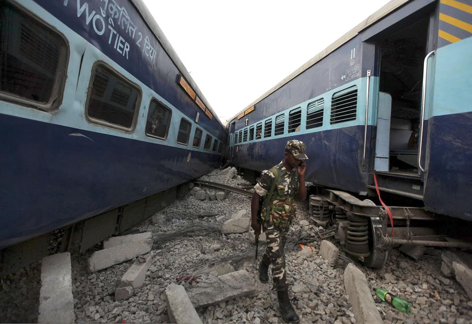 A security personnel speaks on his mobile phone as he walks past damaged coaches of a passenger train after a collision in Khalilabad in the northern Indian state of Uttar Pradesh May 26, 2014. (REUTERS/Stringer)