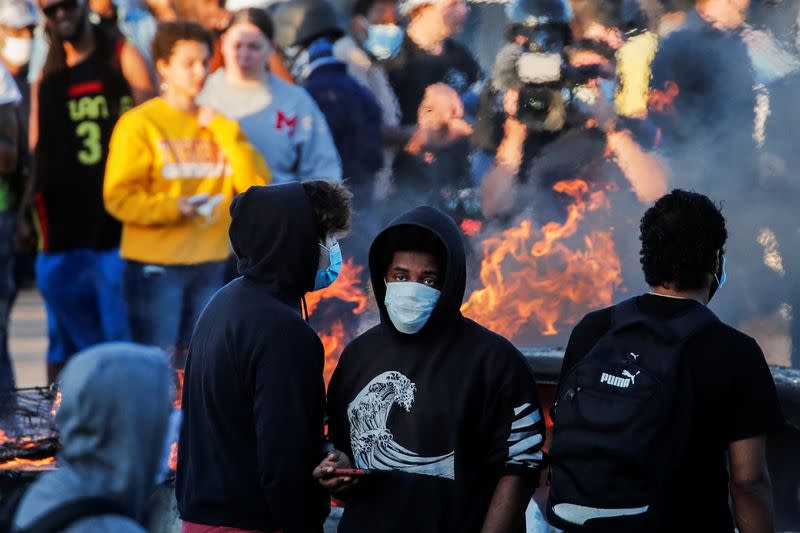 People gather around a burning car at the parking lot of a Target store during protests in Minneapolis