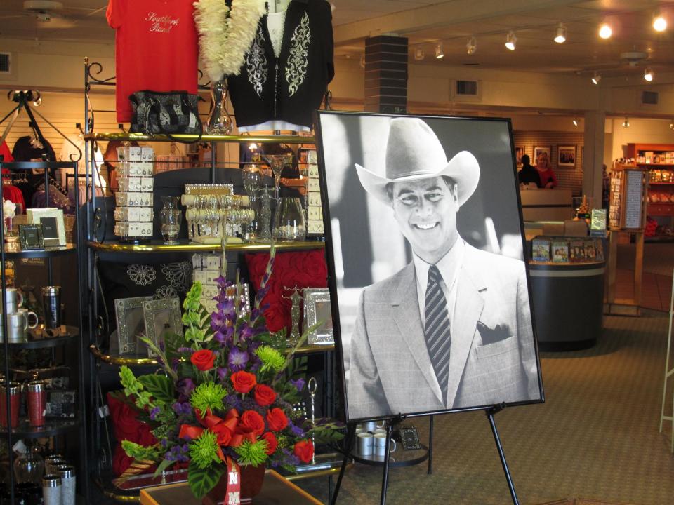 A large portrait of Larry Hagman can be seen by a bouquet of flowers at the entrance of the gift shop at Southfork Ranch on Saturday, Nov. 24, 2012, in Parker, Texas. Officials at the ranch, the setting for the TV series "Dallas" where Hagman played the infamous J.R. Ewing, placed the photo there in memory of Hagman, who died Friday, Nov. 23, 2012 in Dallas. He was 81. (AP Photo/Angela K. Brown)