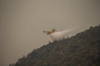 A Spanish firefighting plane pours water on a fire near the Kemerkoy Power Plant, a coal-fueled power plant, in Milas, Mugla in southwest Turkey, Thursday, Aug. 5, 2021. A wildfire that reached the compound of a coal-fueled power plant in southwest Turkey and forced evacuations by boats and cars, was contained on Thursday after raging for some 11 hours, officials and media reports said. (AP Photo/Emre Tazegul)