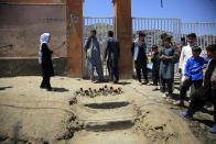 People puts flowers outside a school after a deadly attack on Saturday, in Kabul, Afghanistan, Sunday, May 9, 2021. The May 8 triple bombing of the Syed-Al-Shahada girls school that killed more than 100, nearly 80 of them Hazara students. (AP Photo/Mariam Zuhaib)