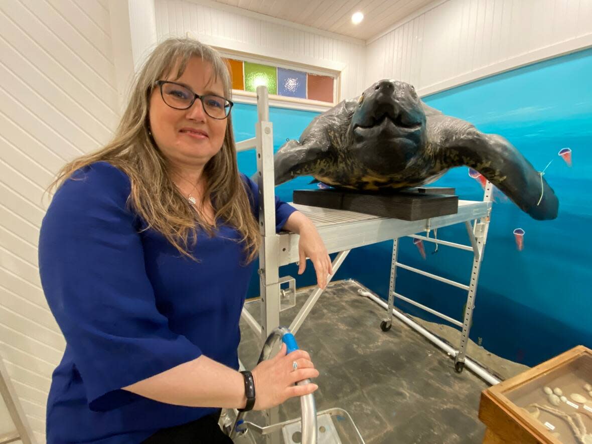 Jennifer Stenhouse poses inside Carr's Wildlife Centre with a fibreglass model of a leatherback sea turtle nicknamed Bob.  (Kirk Pennell/CBC - image credit)