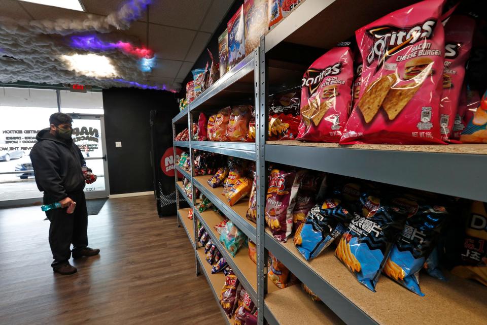 A shopper looks for items in Nap Snacks, Thursday, Jan. 27, 2022 at 1323 W. 86th St. Cousins Ruben Olivares and Sergio Salazar opened the store to sell imported snacks and drinks. Many of the items are common brands like Oreos, Lays and Fanta, but the flavors and forms are not sold in the U.S.