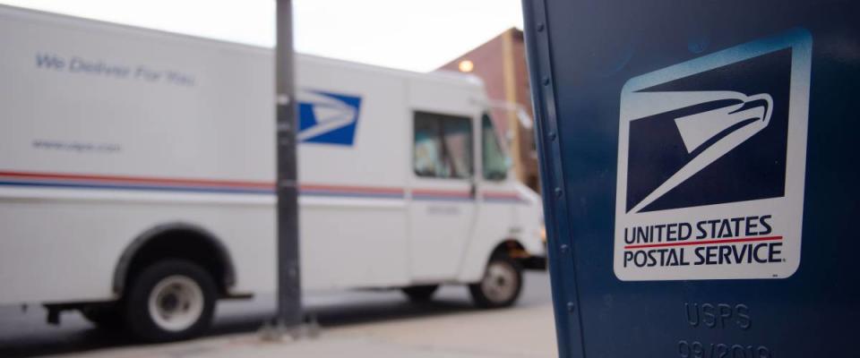 united states postal service truck on street in front of a letter box