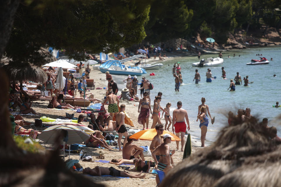 Sunbathers enjoy the beach in Pollença, in the Balearic Island of Mallorca, Spain, Tuesday, July 28, 2020. The U.K. government's recommendation against all but essential travel to the whole of Spain means that all travelers arriving in Britain from that country will have to undergo a 14-day quarantine. (AP Photo/Joan Mateu)