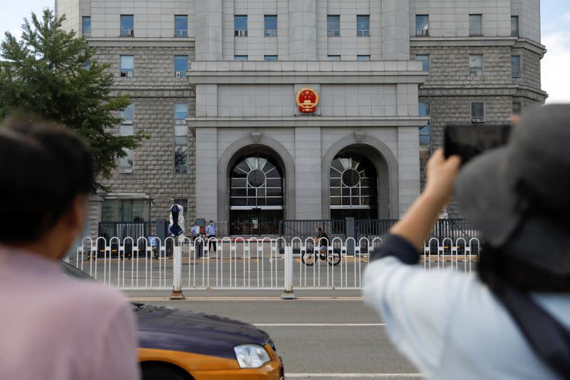 Woman holds a mobile phone in front of Beijing No. 2 Intermediate People's Court