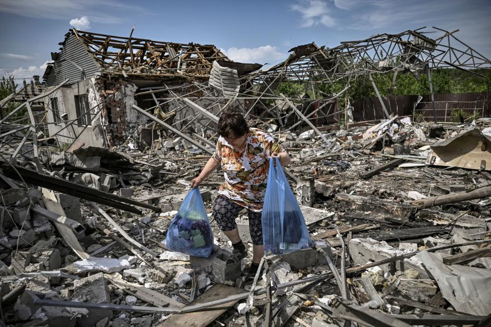 A woman collects belongings in the ruble of their house after a strike destroyed three houses in the city of Slovyansk in the eastern Ukrainian region of Donbas on June 1, 2022.