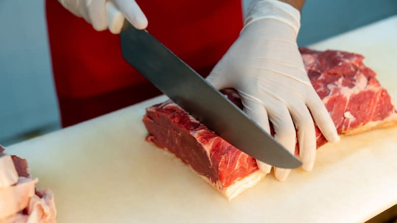 butcher hand cutting meat