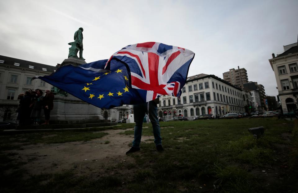 A man unfurls a Union and EU flag outside the European Parliament in Brussels (AP)