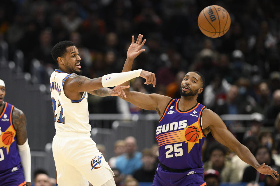 Washington Wizards guard Monte Morris (22) passes the ball away from Phoenix Suns forward Mikal Bridges (25) during the first half of an NBA basketball game Wednesday, Dec. 28, 2022, in Washington. (AP Photo/Nick Wass)