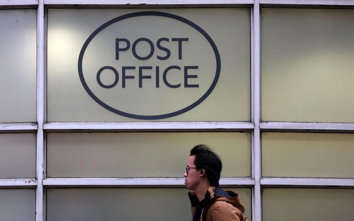 a pedestrian walks past a post office in London