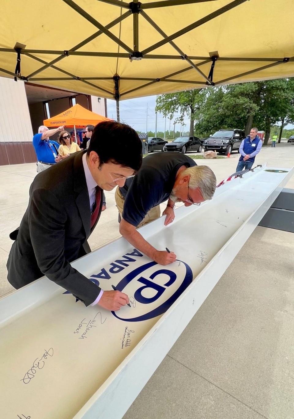 Peter Giorgi, President and CEO of Giorgi Global Holdings, owner of CANPACK and Indiana Gov. Eric J. Holcomb sign the beam before it was hoisted into place during the topping off ceremony at the CANPACK plant in Muncie.