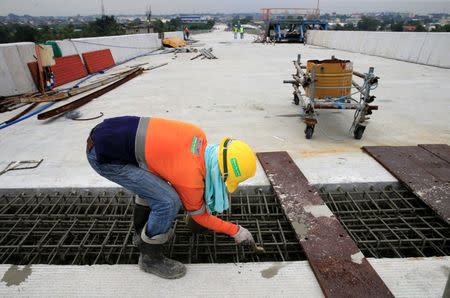 A construction worker stands over the newly dried concrete and secure linking steel bars of the 5.58 kilometre elevated highway in Caloocan City, metro Manila, Philippines on August 2, 2017. REUTERS/Romeo Ranoco