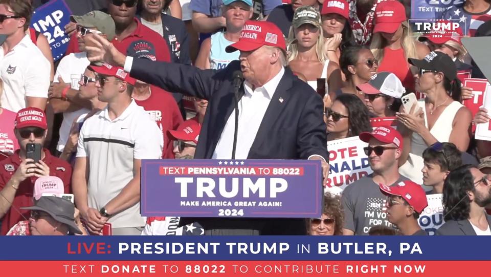 A screen grab captured from a video shows Republican presidential candidate former President Donald Trump speaking at a podium shortly before gunshots were reported during a rally.