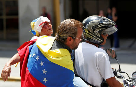 An opposition supporter is helped after being injured by a tear-gas canister in a rally against Venezuela's President Nicolas Maduro in Caracas. REUTERS/Christian Veron
