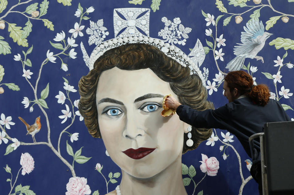 Workmen install a new mural by Frederick Wimsett, of Britain's Queen Elizabeth II to mark her 90th birthday celebrations, in central London, April, 19, 2016. (AP Photo/Alastair Grant)