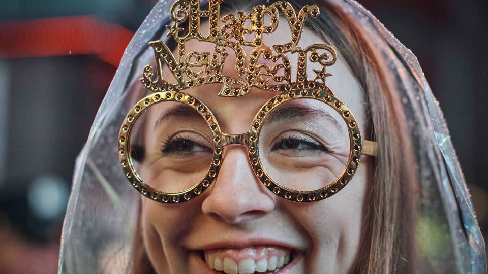 A reveller wearing New Year glasses smiles under the rain during the New Year's Eve celebrations in Times Square on Saturday, Dec. 31, 2022, in New York. - Andres Kudacki/AP