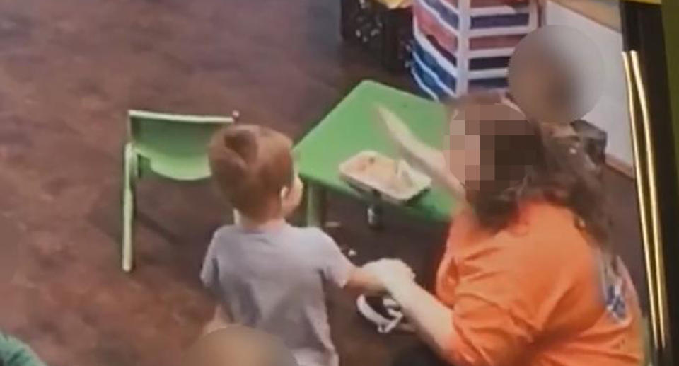 A still from the surveillance video shows a staff member raising her hand to a child's face.