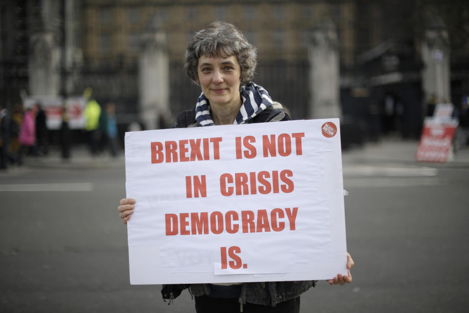 Leave the European Union supporter Eleanor Dobson, aged 54 from Cambridge, poses for photographs backdropped by the Houses of Parliament in London, Wednesday, Feb. 13, 2019. Eleanor believes leaving the European Union with a clean break would be the best way forward. With Brexit only days away, it is in the grounds outside parliament that the true believers gather each day to try to influence lawmakers, call attention to their cause, and bring new supporters into the fold. (AP Photo/Matt Dunham)