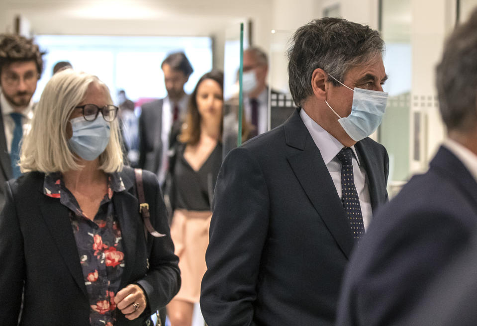 France's former Prime Minister Francois Fillon, right, and his wife Penelope wear protective masks as they arrive at Paris courthouse, in Paris, Monday, June 29, 2020. A Paris court is set to render or postpone a verdict in the fraud trial of former Prime Minister Francois Fillon on Monday. (AP Photo/Michel Euler)