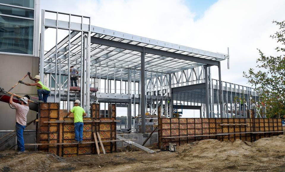 Construction workers pour concrete as crews assemble the steel framing for the new visitor center and mooring point for the LST 325.