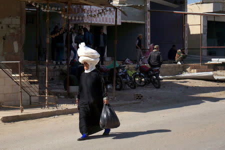 A woman carries bread on her head as she walks along a street in the rebel held al-Ghariyah al-Gharbiyah town, in Deraa province, Syria February 28, 2016. REUTERS/Alaa Al-Faqir