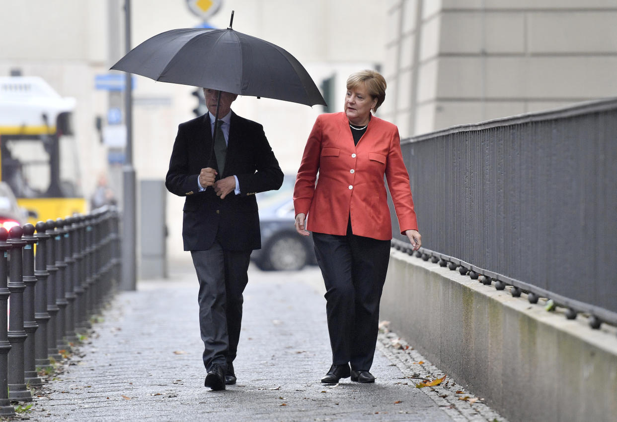Sonntagnachmittag in Berlin: Angela Merkel und ihr Mann feilschen um einen Regenschirm. (Bild: AP Photo)