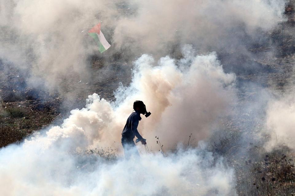 16 December 2022: A demonstrator stands amidst tear gas smoke, fired by Israeli soldiers, following a protest in Beit Dajan (AFP/Getty)