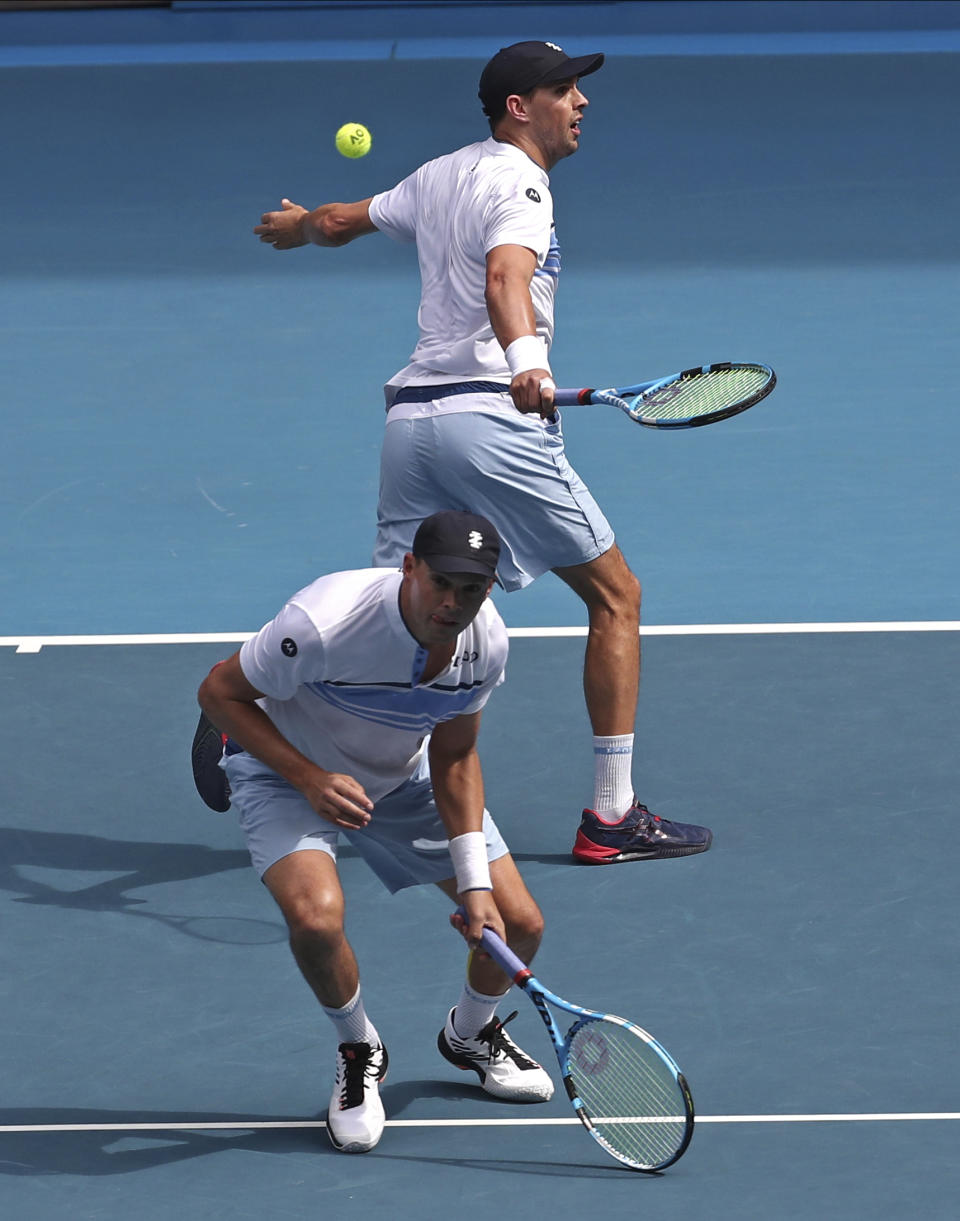 Mike Bryan, top, of the U.S. and his brother Bob play during their third round doubles match against Croatia's Ivan Dodig and Slovakia's Filip Polasek at the Australian Open tennis championship in Melbourne, Australia, Monday, Jan. 27, 2020. (AP Photo/Dita Alangkara)