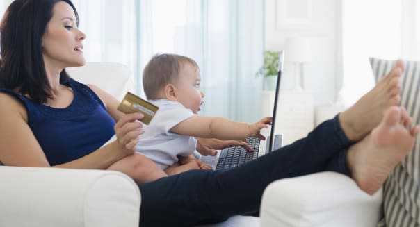 Mixed race mother holding baby and shopping on laptop